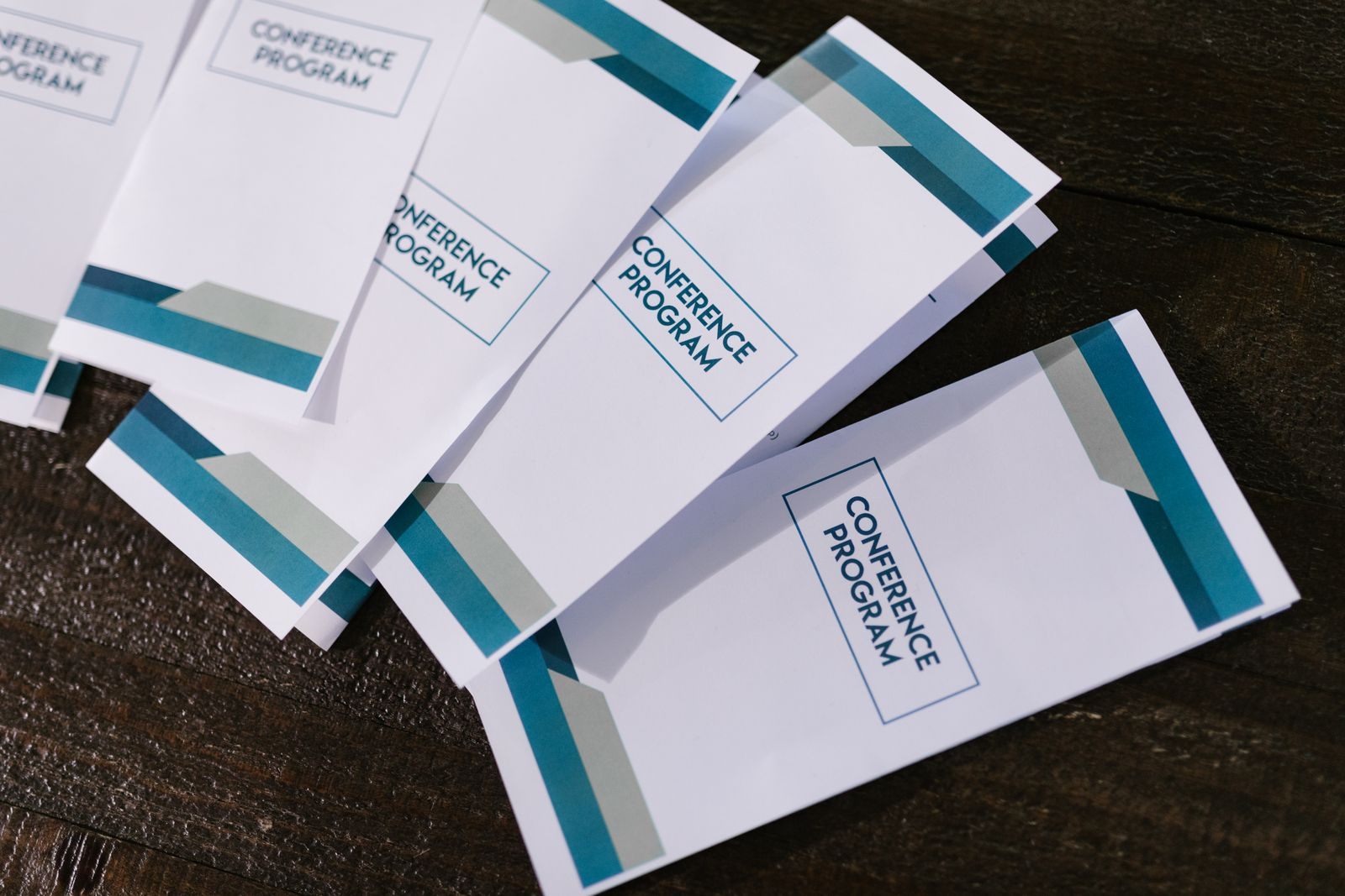 Printed event leaflets fanned out on a wooden table, like the invitations behind a cruise travel expo scam warning