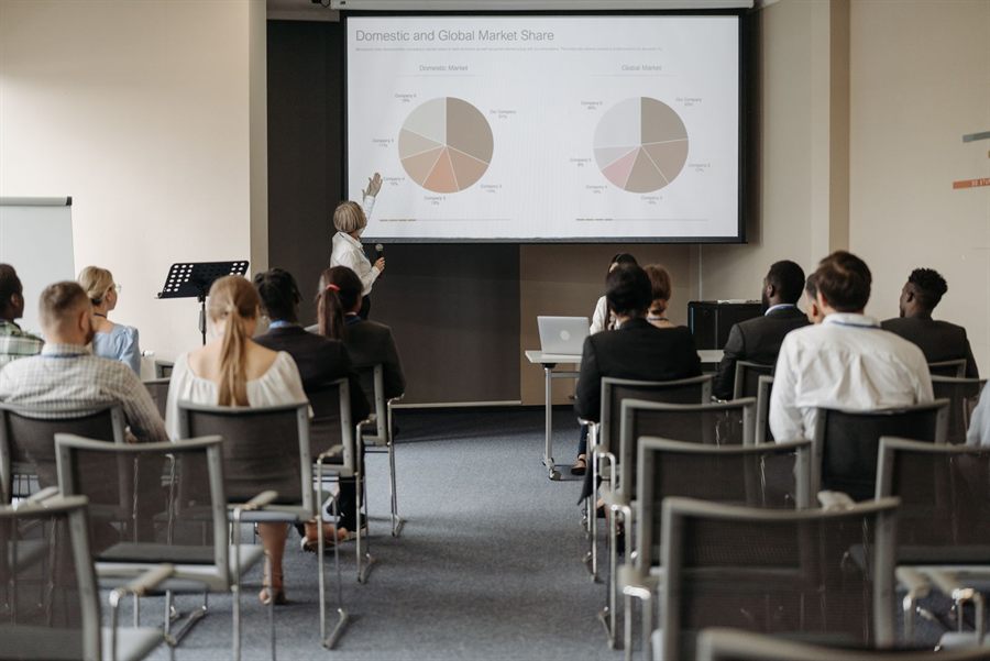 Small seminar audience watching a presenter with charts on screen